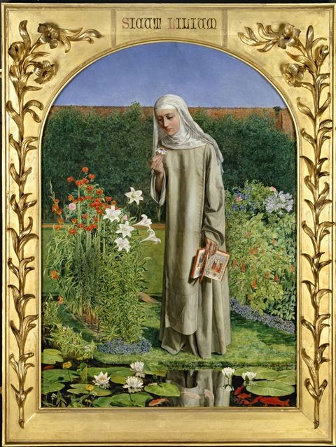 Painting. A pale-skinned woman wearing a white nun’s habit that covers her head, neck, and shoulders over an off-white robe stands in a garden. She is reflected in a pond near her feet. She holds an open book by her side and looks at a white flower she holds in her other hand. The painting has an arched top and is set in a gold frame with lilies in relief up each side.
